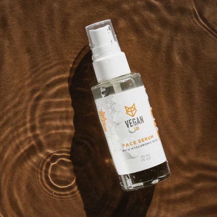 Vegan Fox Face Serum med Hyaluronic Acid i genomskinlig glasflaska med vit pumpspray, 30 ml, på träyta med solskuggor