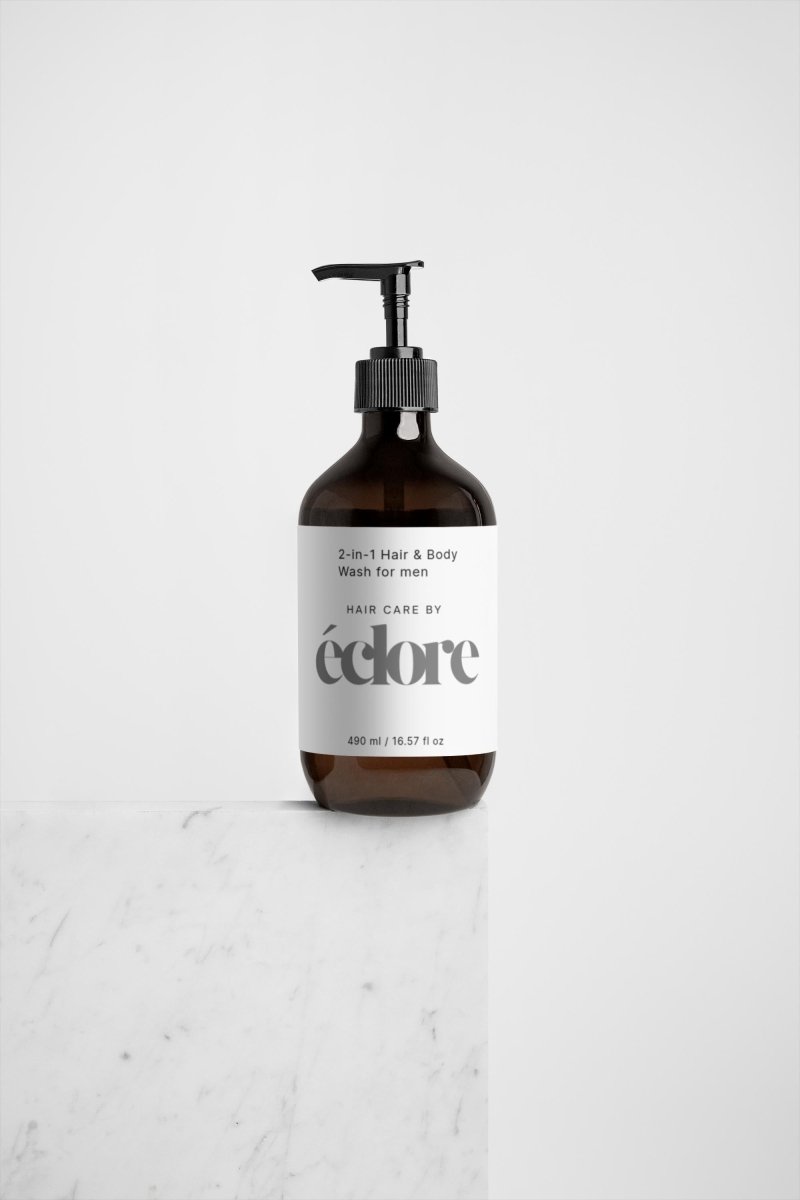 Brun glasflaska med pumpmunstycke innehållande éclore 2-in-1 Hair & Body Wash for men, 490 ml med vit etikett