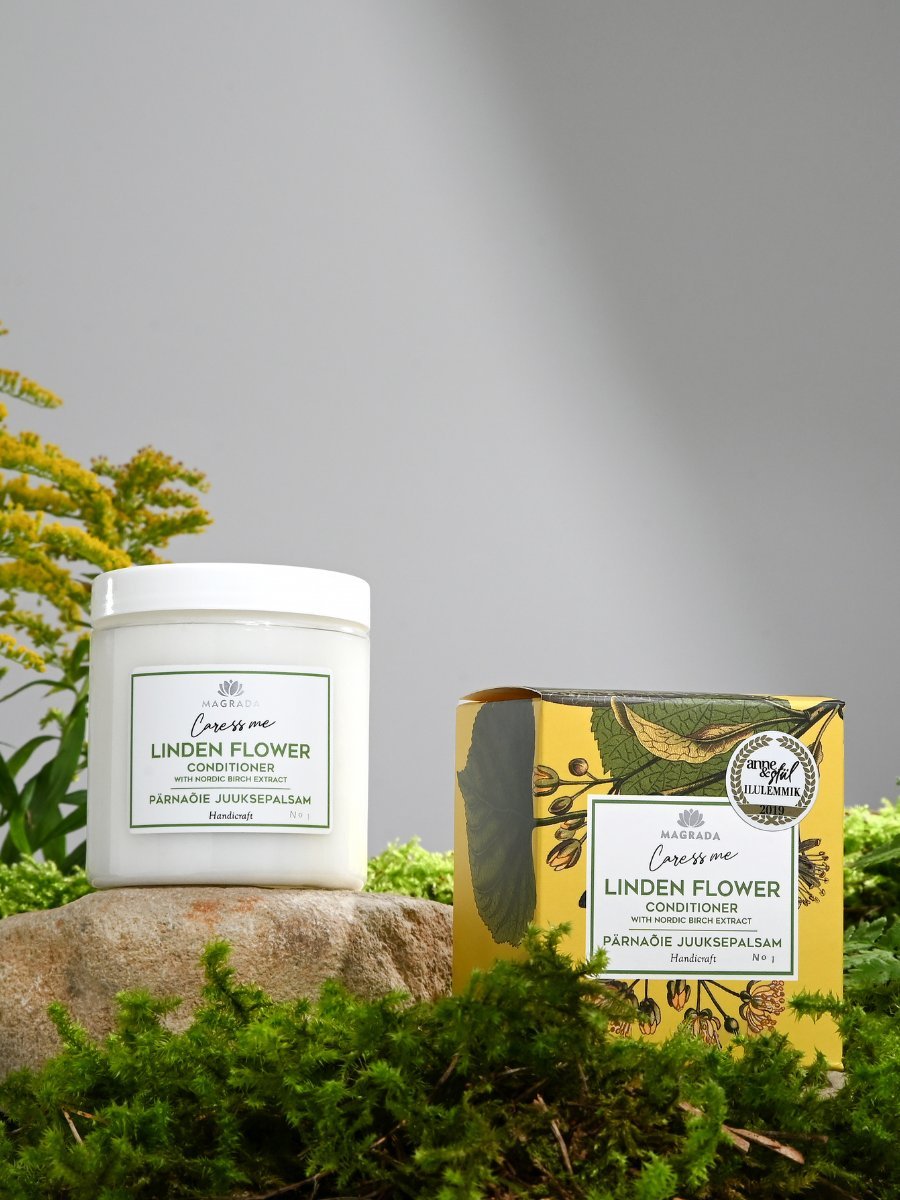 Vit burk med Linden Flower Conditioner balsam med lindblomma och björkextrakt bredvid gul förpackning omgiven av grön mossa