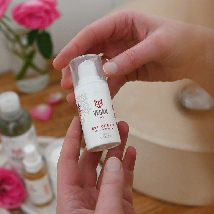 Vit pump-flaska med Anti-Wrinkle ögonkräm 15 ml hålls i händer, vegan hudvård med röd logotyp