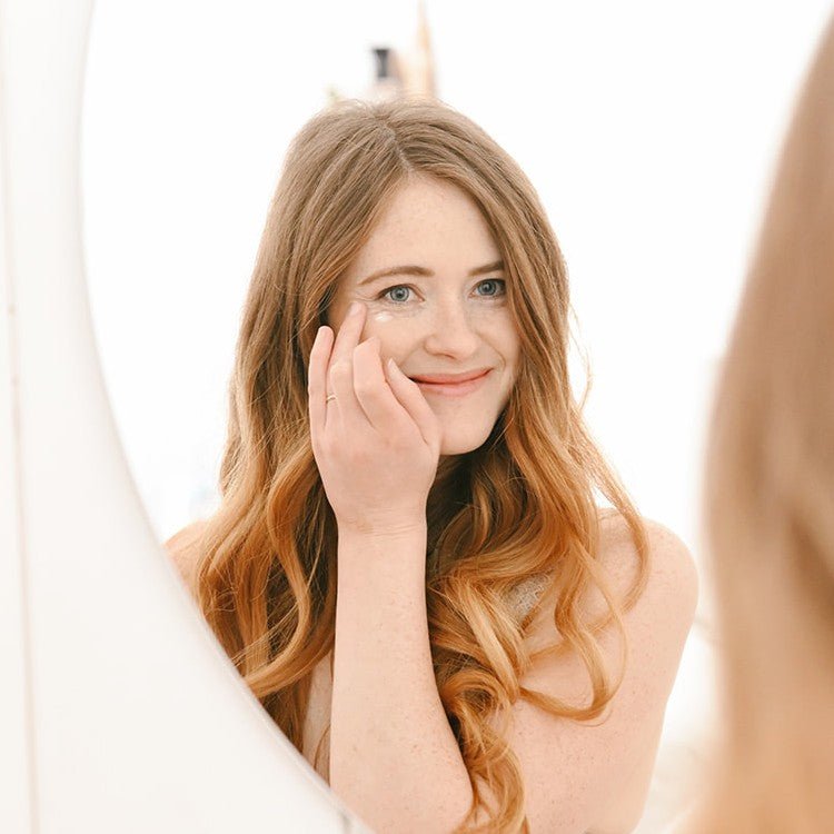 Kvinna applicerar hudvård runt ögonen med fingertopparna - Anti-Wrinkle ögonkräm för mogen hud