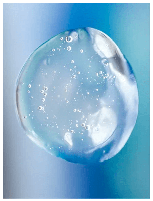 Transparent droppe av Clarifying Gel for Men med bubblor och kristallklar textur mot blå bakgrund