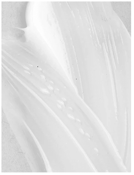 Vit krämtextur av Moisturising Day Cream med Hyaluronsyra smetas ut på ljus hud och visar den silkeslena konsistensen