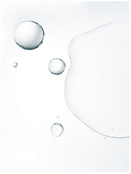 Genomskinliga vattendroppar och bubblor på vit yta som illustrerar Glycolic Acid Exfoliating Toner 250 ml