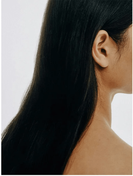Kvinna med långt mörkt hår som visar resultat av Keratin Shine Leave-In Hair Mist - glansigt och silkeslent hår