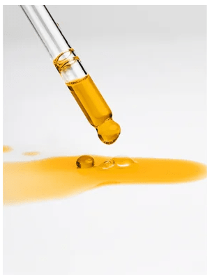 Nourishing Facial Oil droppas från pipett - gyllengul olja i glasbehållare mot vit bakgrund