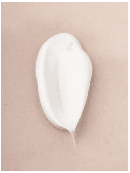 Vit krämklick av Sensitive Skin Body Cream på beige bakgrund, visar produktens mjuka och återfuktande textur