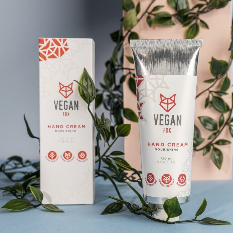 Vit tub med närande handkräm med sheasmör 120ml och matchande förpackning, omgiven av gröna växter