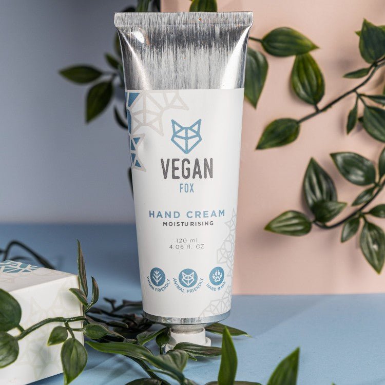 Vit handkrämstub med silvertopp från Vegan Fox, fuktgivande handkräm 120 ml, omgiven av gröna växter