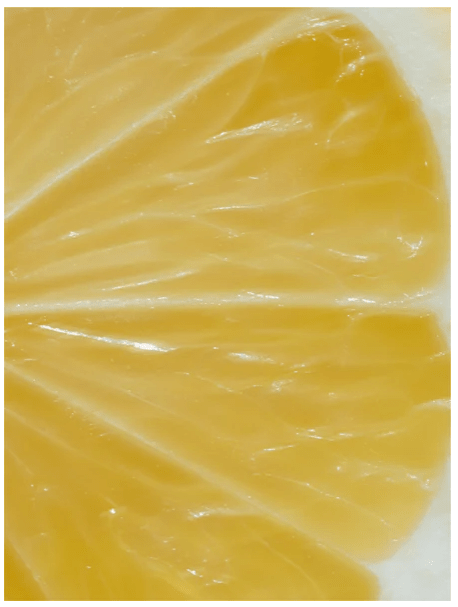 Närbild på citrusskiva med gul fruktkött och vita skiljeväggar, symboliserar vitamin C i Vitamin C Serum