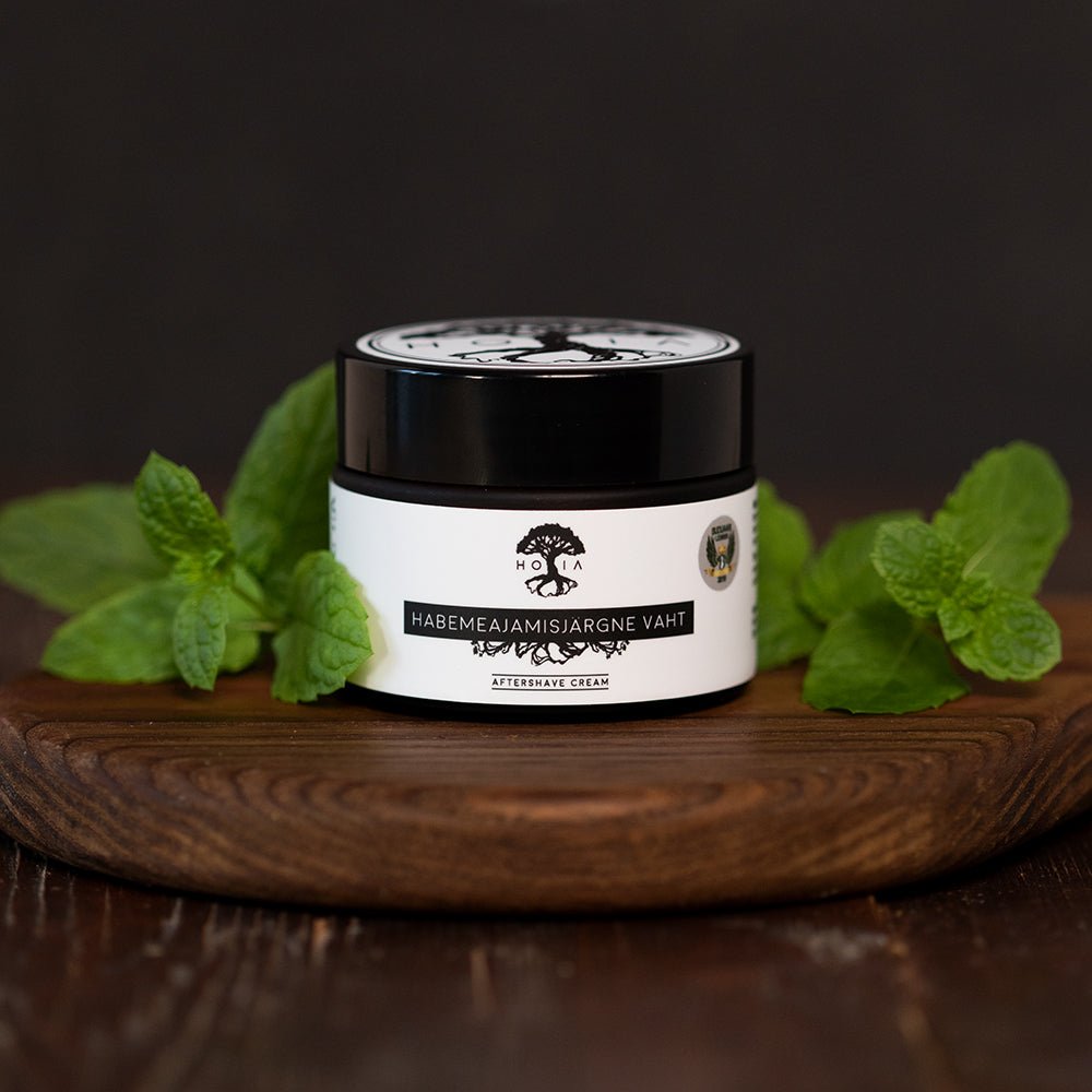 Burk med naturlig aftershave balm för män från HOIA, omgiven av myntablad på träbricka