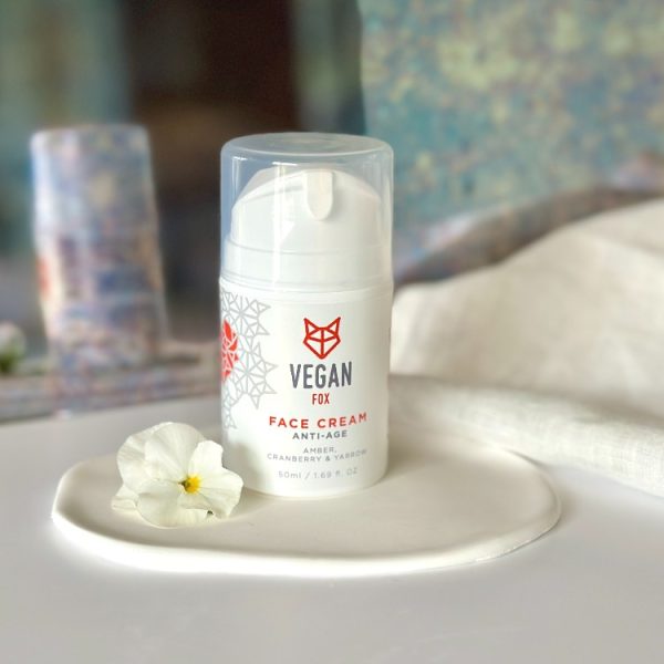 Vit pumpflaska med Vegan Fox Anti-Age Face Cream 50ml på vit tallrik med vit blomma bredvid