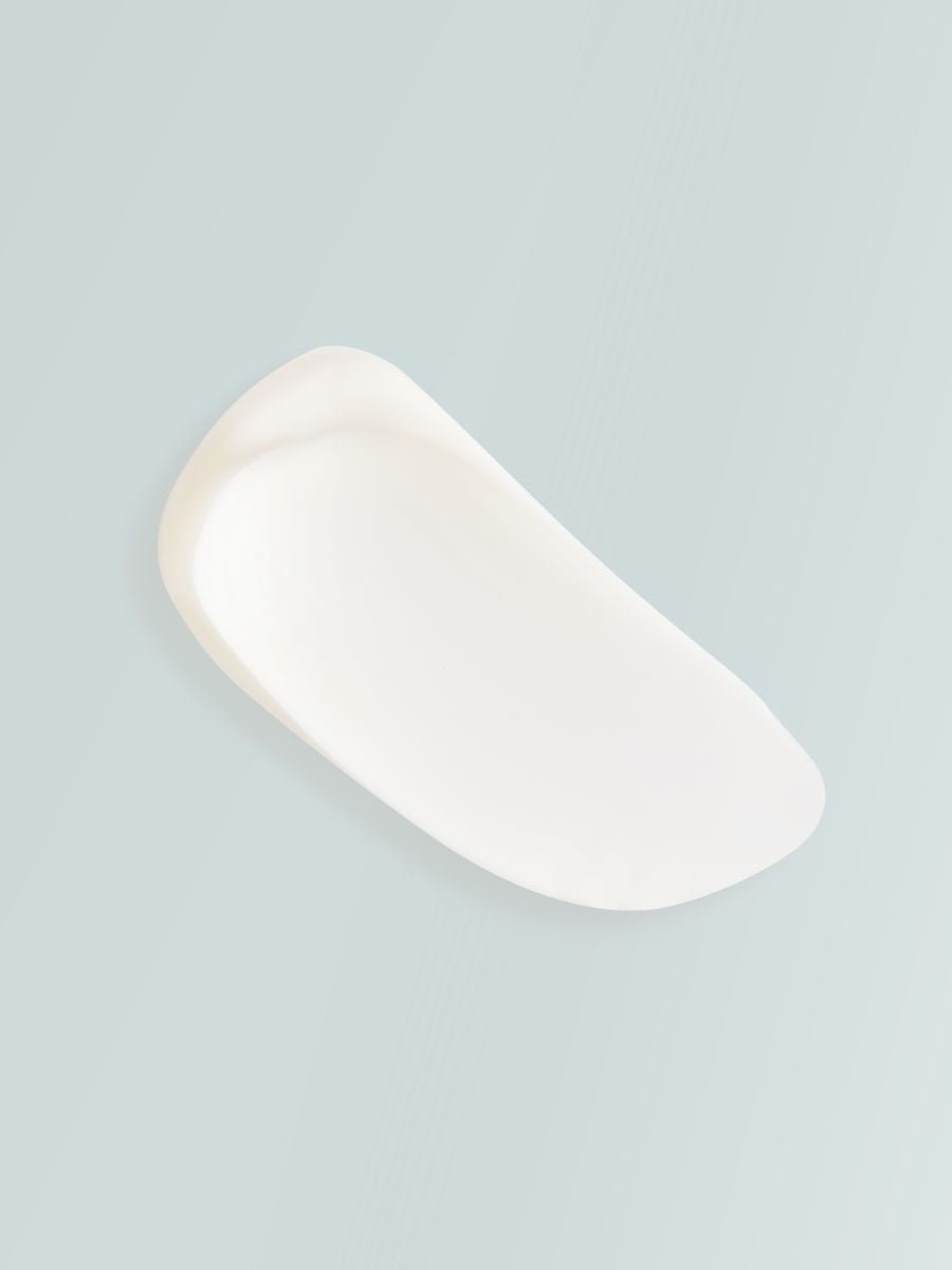 Vit krämklick av åtstramande body cream med alger och växtextrakt på grå bakgrund