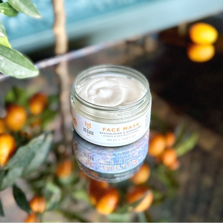 Öppen glasburk med Revitalising & Hydrating Face Mask, vit cremig textur, vegan märkning, naturlig miljö med orangea bär