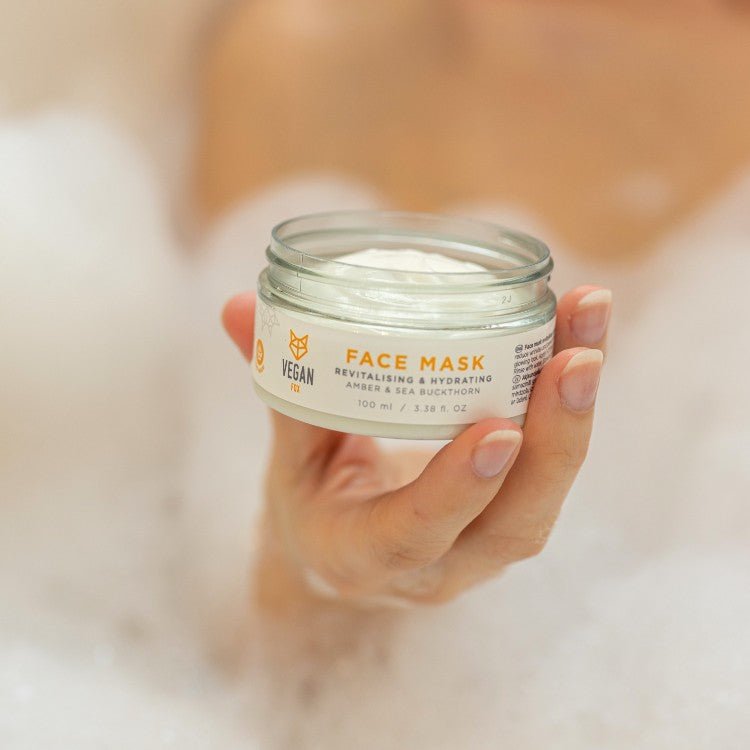 Revitalising & Hydrating Face Mask i genomskinlig glasburk med vit kräm, hålls i hand mot neutral bakgrund