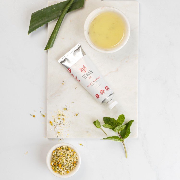 Fotkräm 120ml i vit tub med silver lock, omgiven av aloe vera, kamomillblommor, honung i skål och mynta