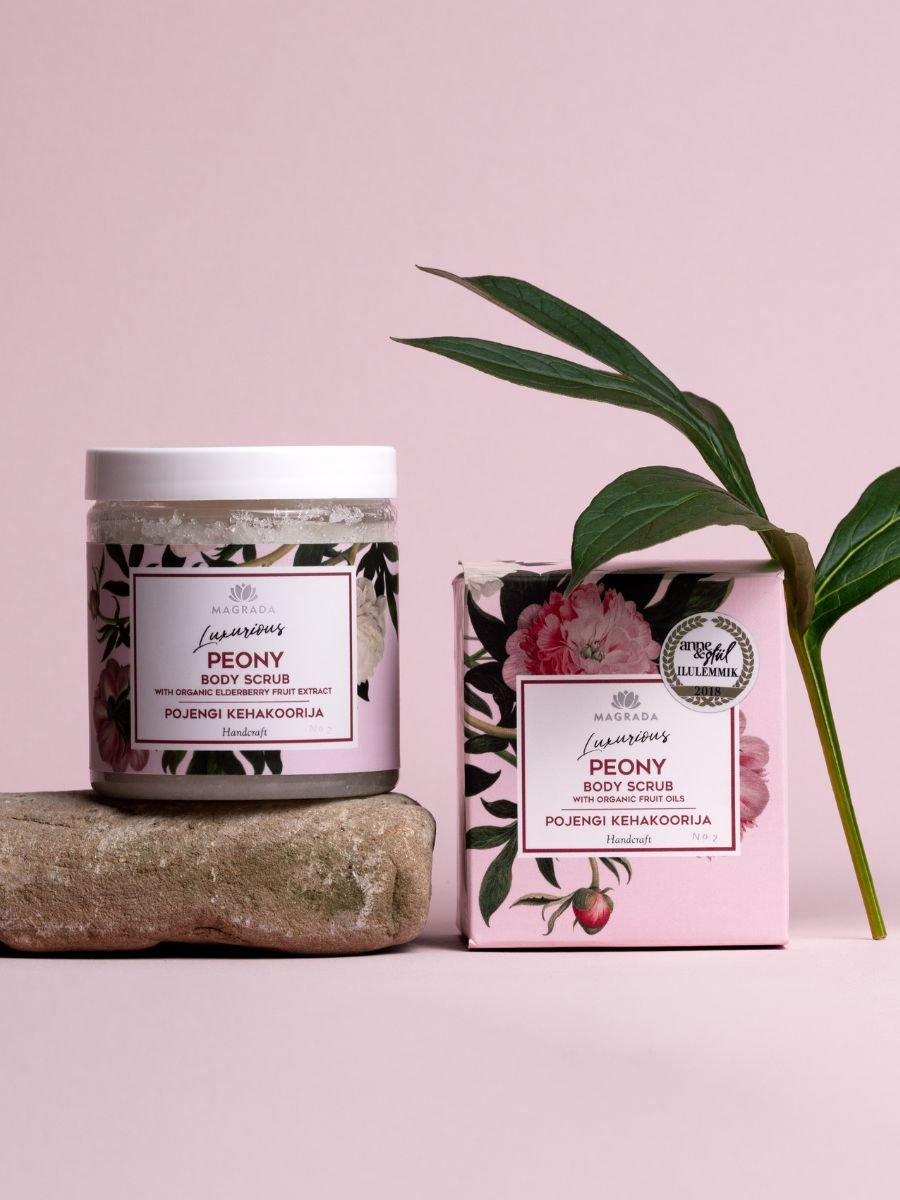 Body Scrub med Pionarom i glasburk med vit lock och rosa förpackning med blommönster på natursten