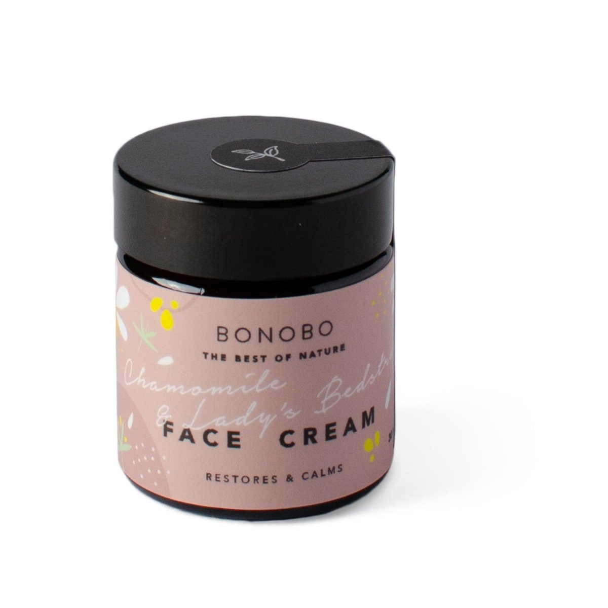 Rund glasburk med svart lock innehållande Ansiktskräm Kamomill och Måra från Bonobo, rosa etikett med vit text