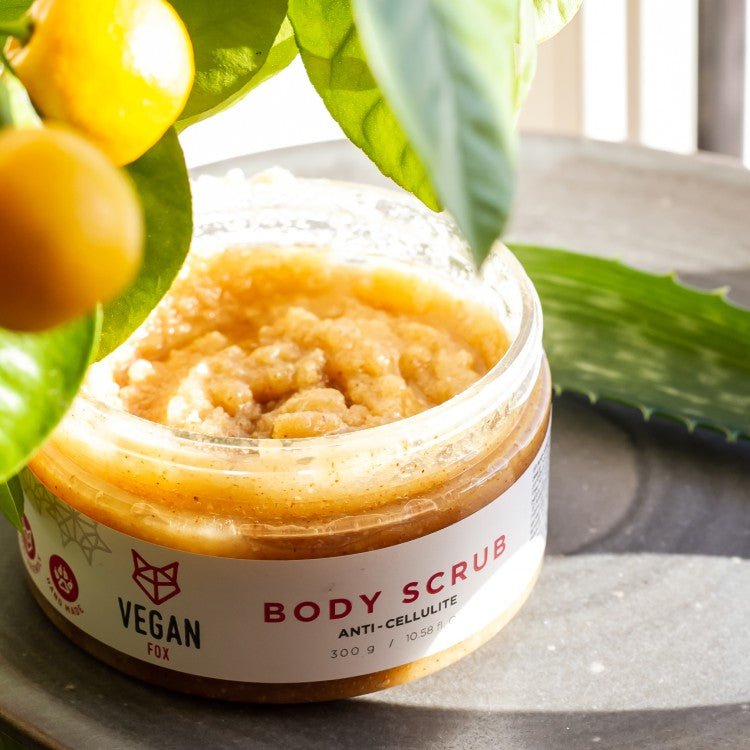 Öppnad burk med Anti-cellulite Body Scrub Ingefära som visar gul-orange körningsmedel med grovkornig textur