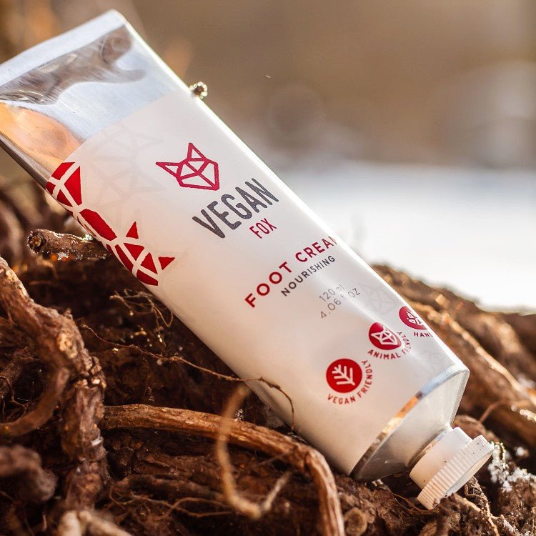 Vit tub med fotkräm från Vegan Fox, 120ml, med rosa logotyp och text, placerad på naturlig bark i solljus