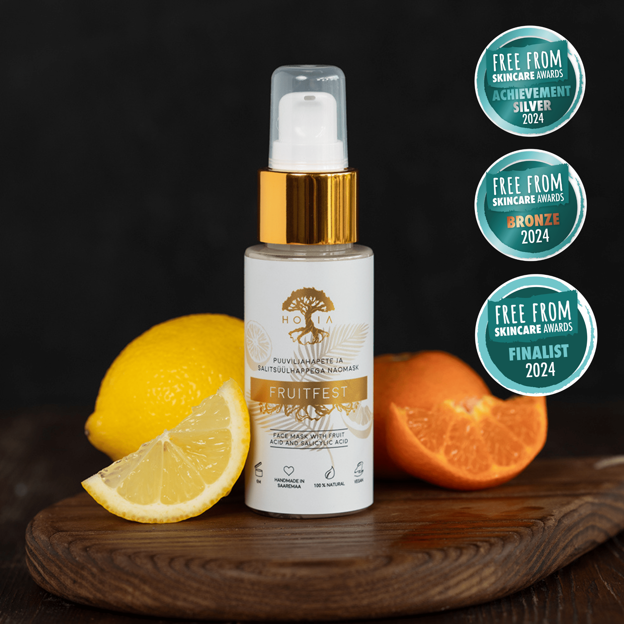 Fruitfest Face Mask i vit sprayflaska med gulddetaljer, omgiven av citrusfrukt på träbricka