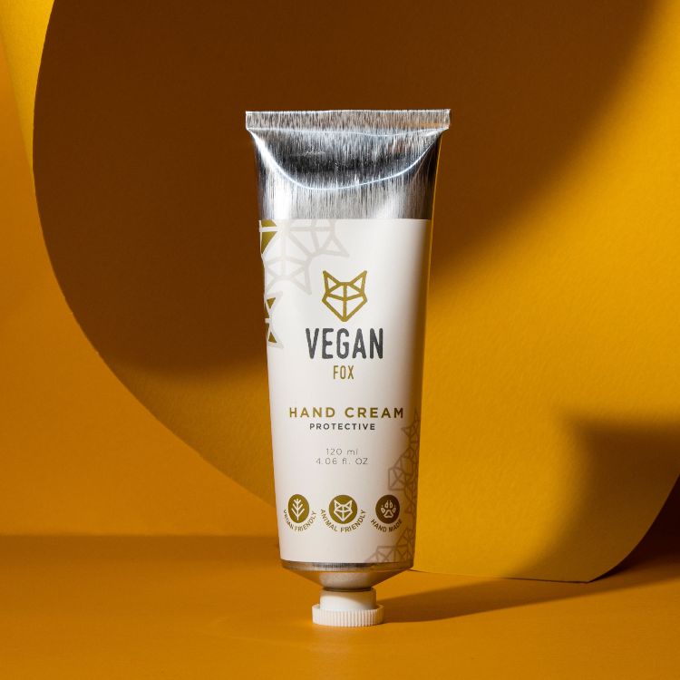 Vit tub med skyddande handkräm med mangosmör, silverfärgad kork, gulddetaljer, 120 ml, mot gul bakgrund