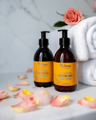 Nurme hand- och kroppslotion med havtorn bland rosenblad och vit handduk