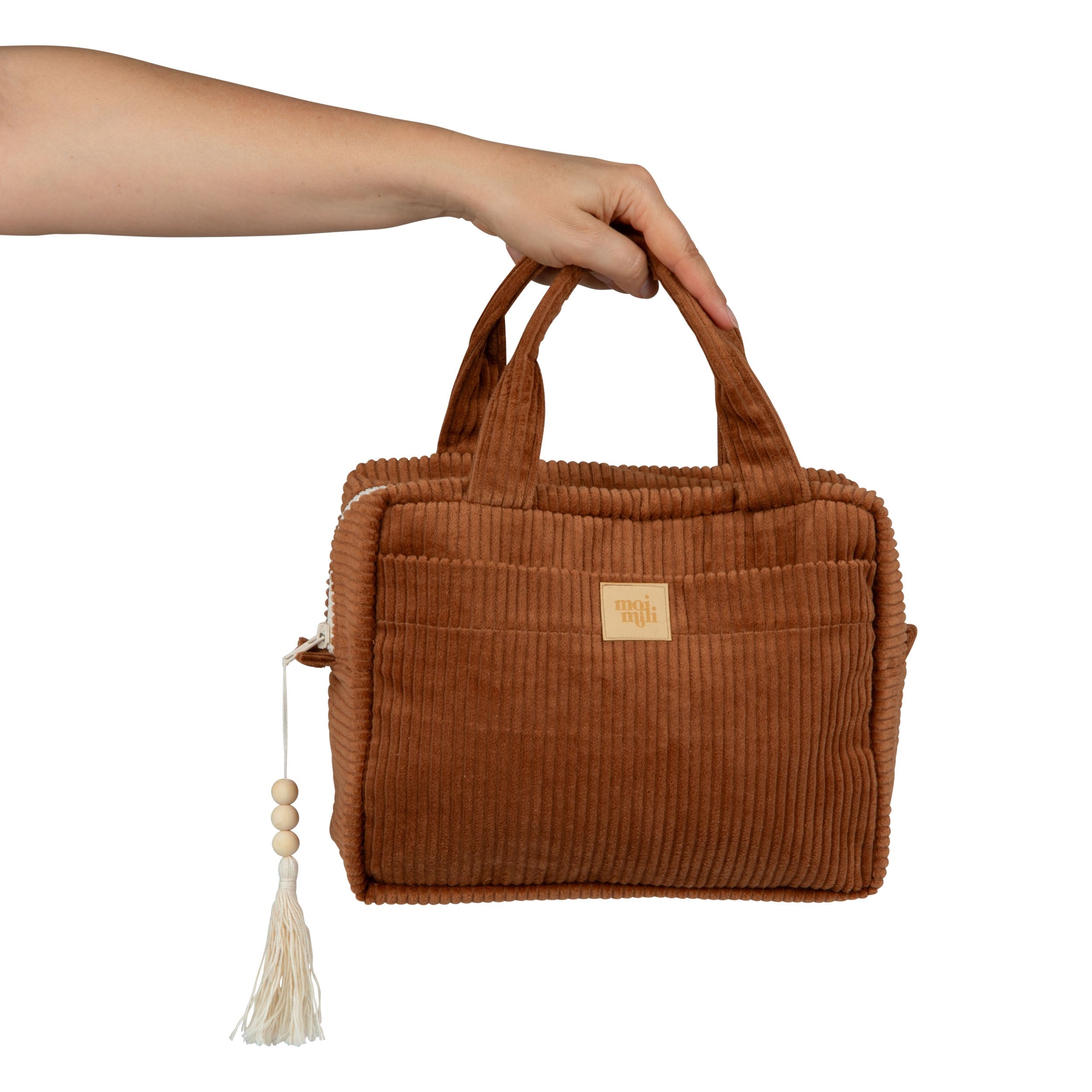 Large Make-Up Bag Caramel - brun manchester necessär med handtag, tofs och märkeslogga hålls av hand