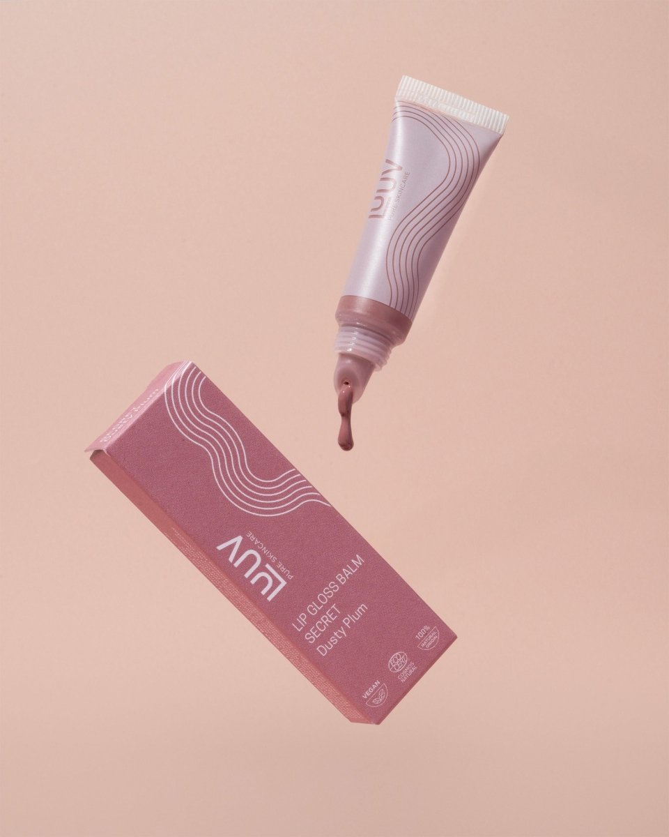 Anni läppbalsam Perfect i rosa tub med vit kork, dusty plum färg droppar ut, rosa förpackning på persikofärgad bakgrund