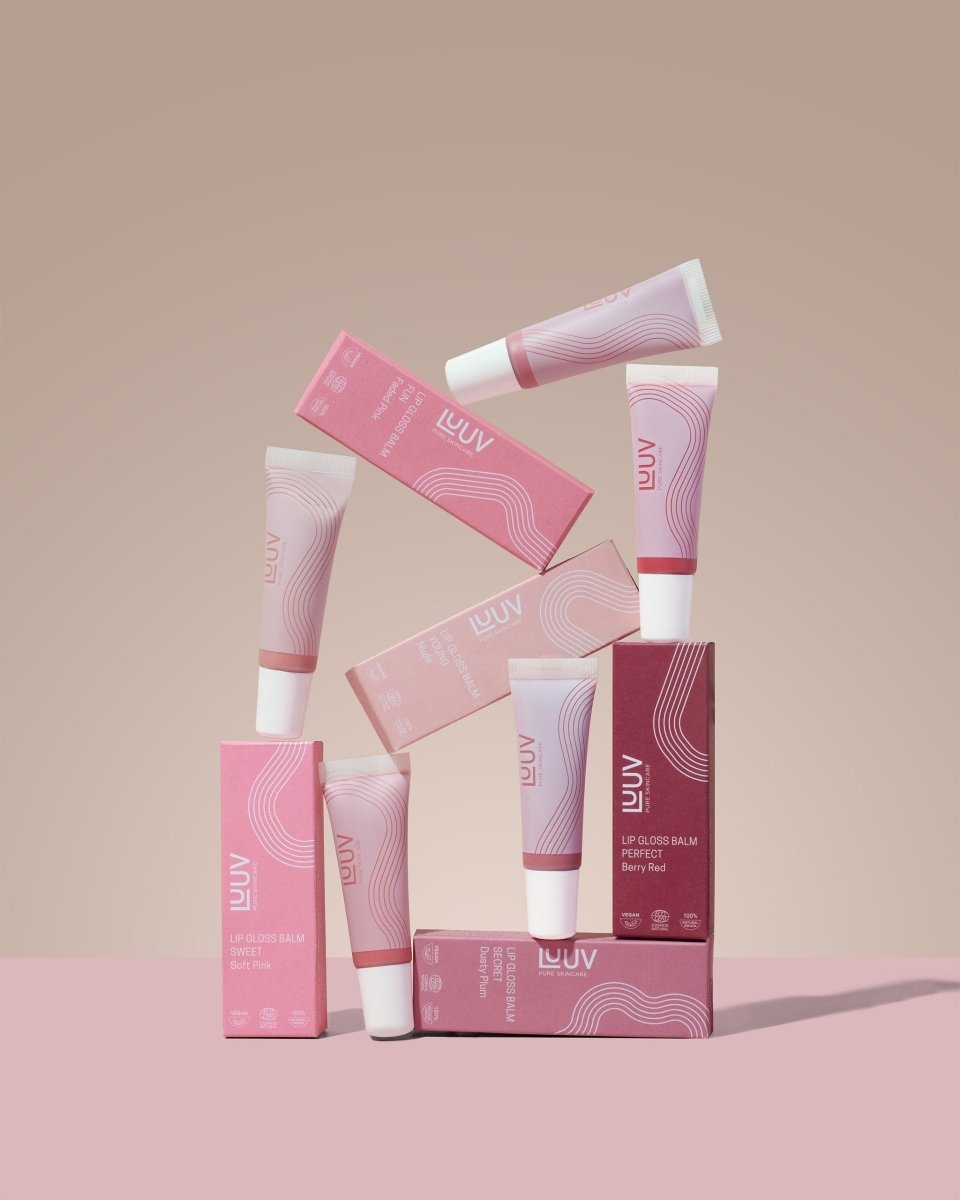 LUUV läppbalsam i rosa förpackningar med våglinjemönster, tuber med vita lock arrangerade på beige bakgrund