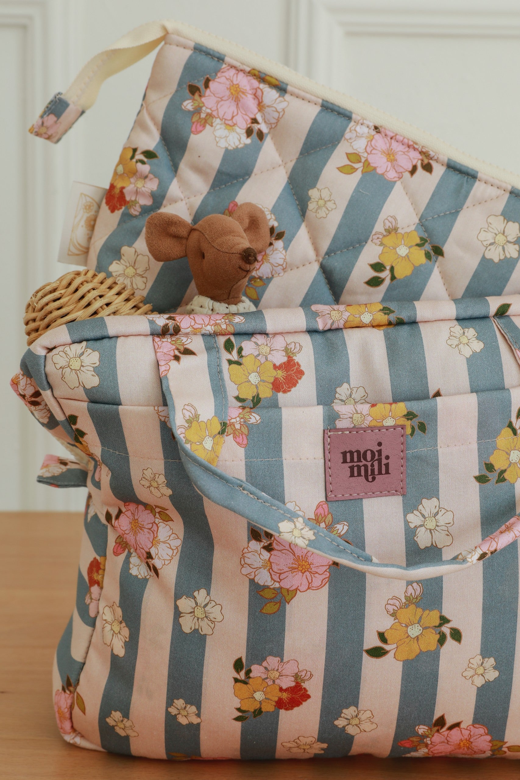 Make-Up Bag Set blå randigt med blommönster, två necessärer i korg med bruna handtag och rosa märkning