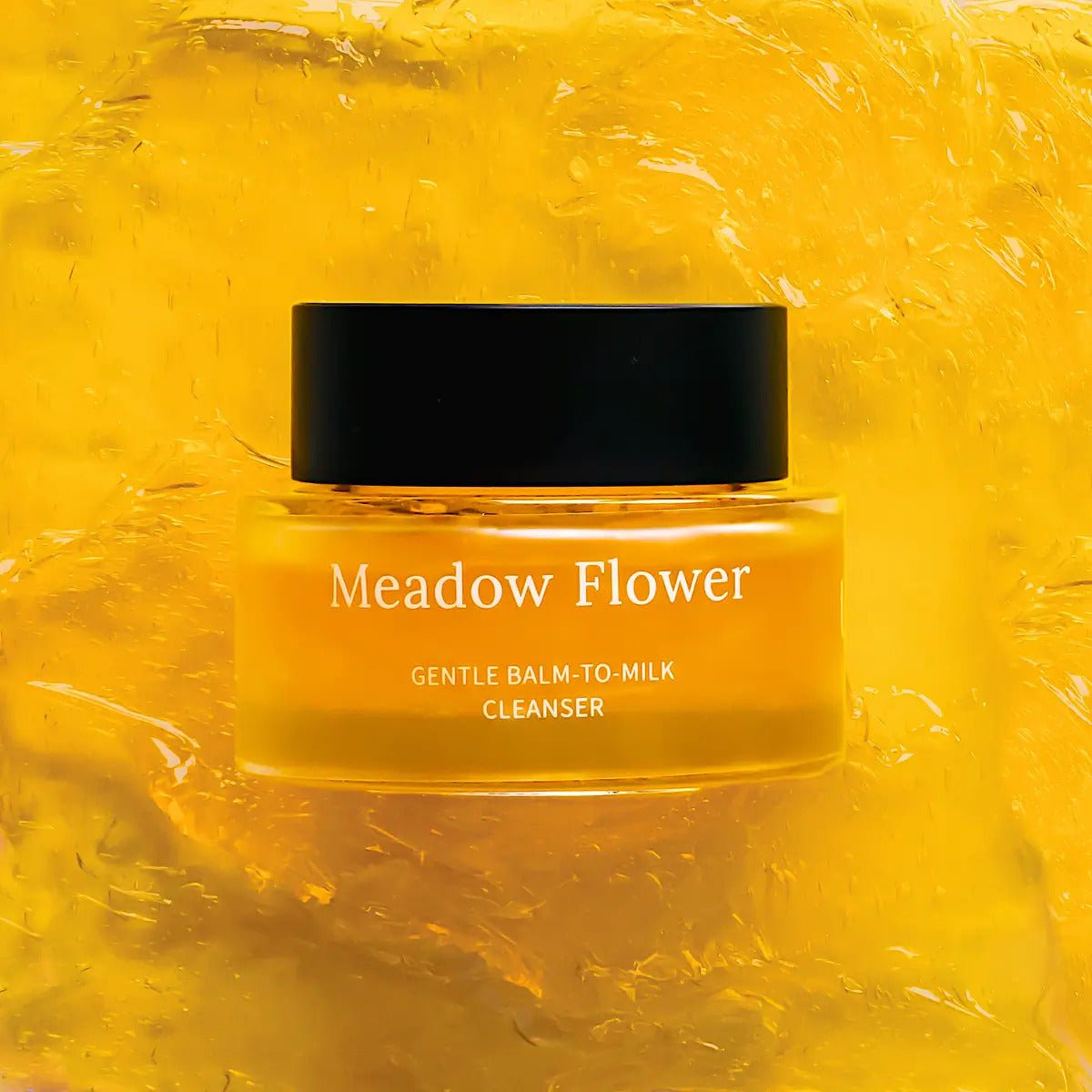 Meadow Flower Gentle Balm-to-Milk Cleanser i gul glasburk med svart lock mot gul honungsliknande bakgrund