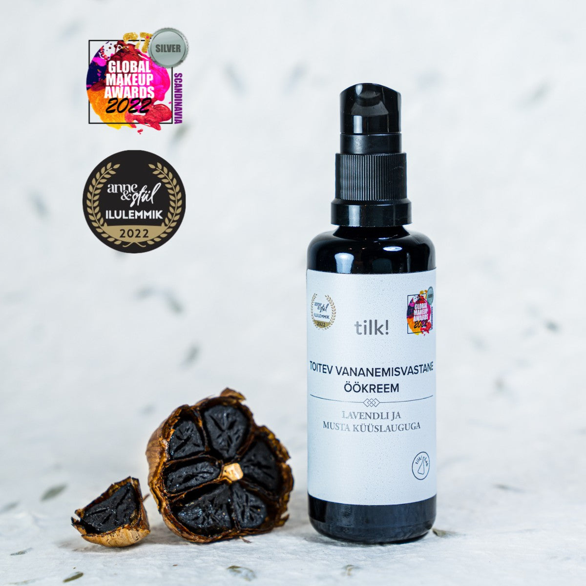 Närande Anti-Age Nattkräm med Lavendel och Svart Vitlök i svart pumpflaska med vit etikett, 50ml, bredvid svarta vitlöksklyftor