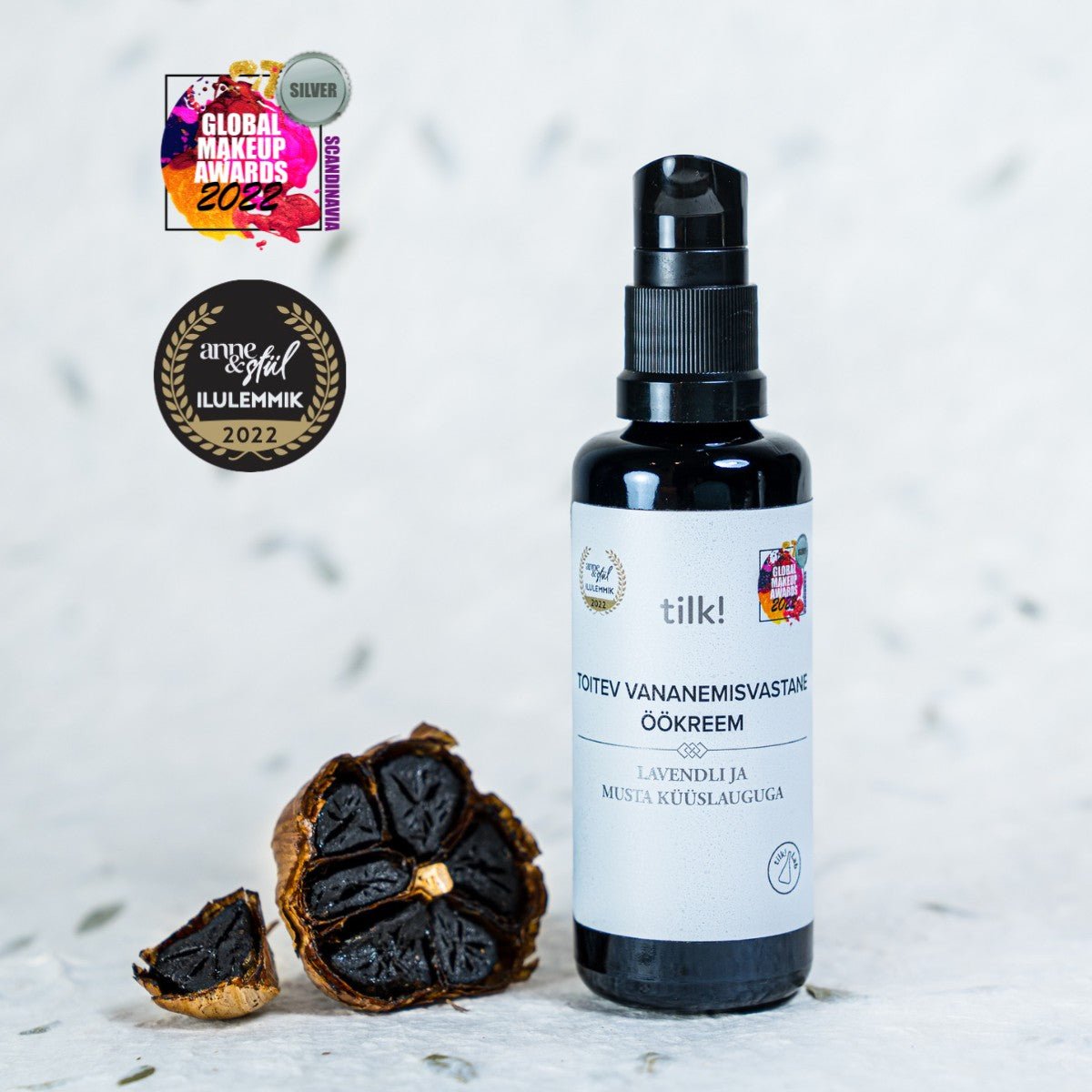 Närande Anti-Age Nattkräm med Lavendel och Svart Vitlök i svart pumpflaska med vit etikett, 50ml, bredvid svarta vitlöksklyftor