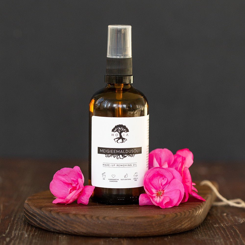 Natural Makeup Remover Oil i amber glasflaska med spraypump och vit etikett, dekorerad med rosa blommor