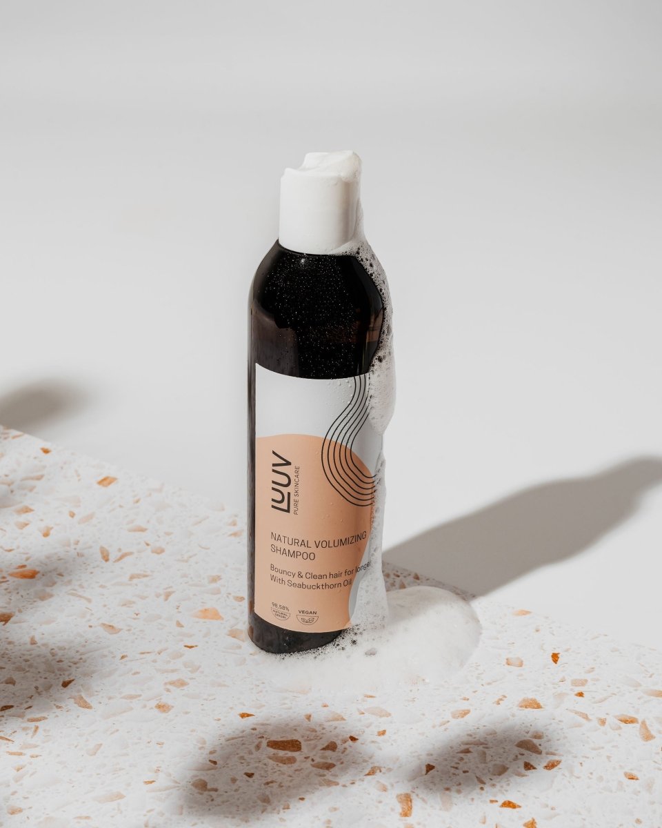 Naturligt havtornsschampo i 250ml flaska med vit kork, mörk vätska och persikofärgad etikett på marmorbakgrund