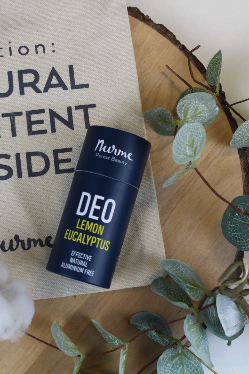 Mörkblå cylinderformad deodorantstick från Nurme med texten DEO LEMON EUCALYPTUS, omgiven av gröna eukalyptusblad