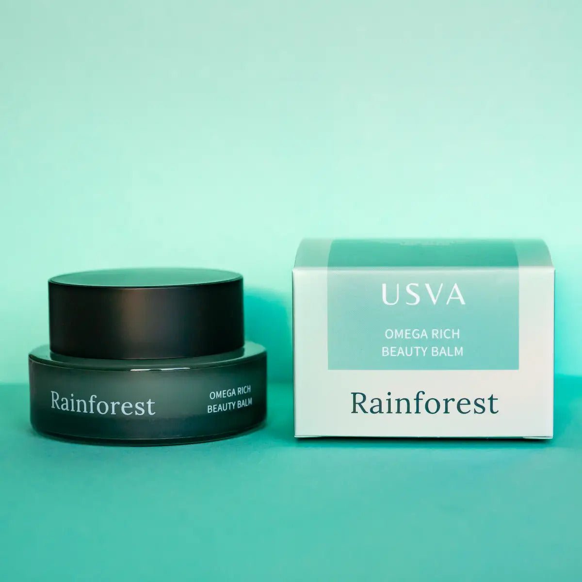 USVA Rainforest Omega Rich Beauty Balm i mörkgrön burk med matchande vit-grön förpackning på turkos bakgrund