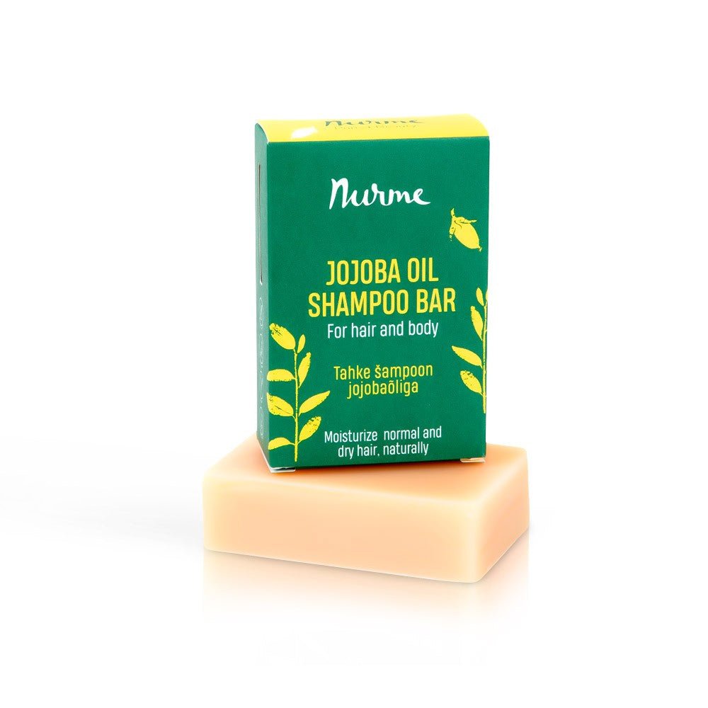Nurme schampokaka med jojobaolja i grön förpackning bredvid ljus tvålbar, 100 g