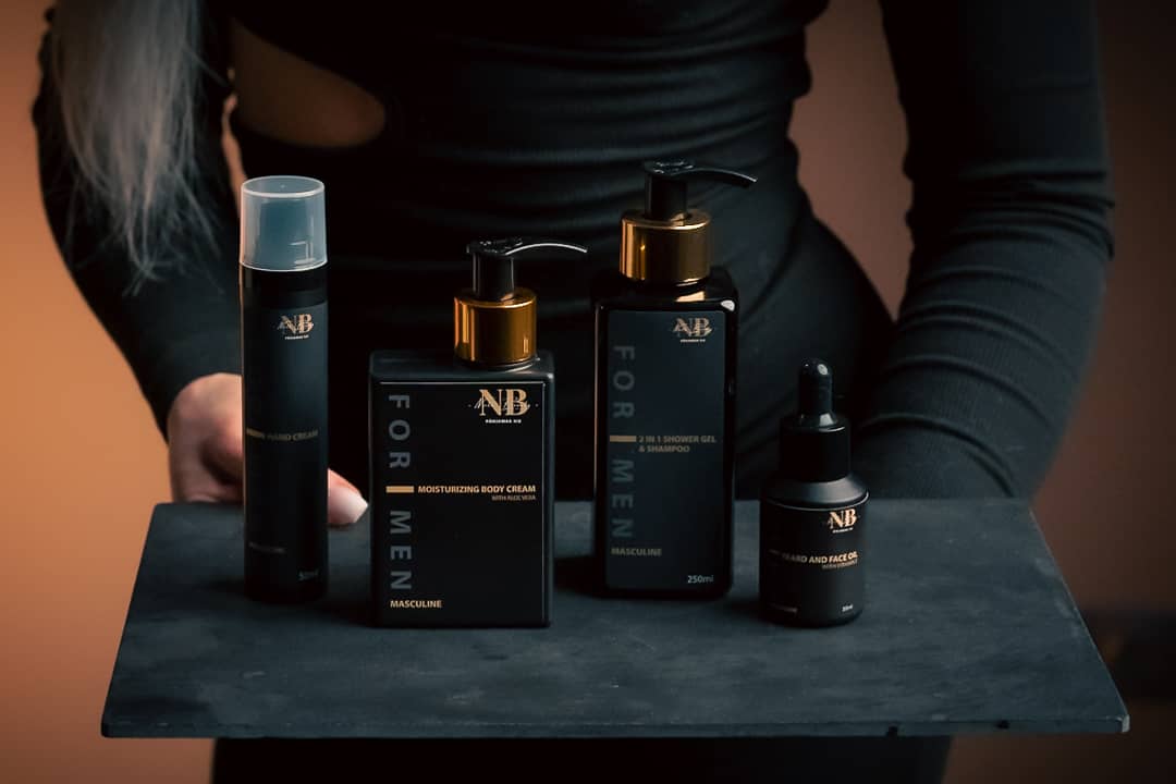 NB For Men produktserie i svart och guld – skäggolja, ansiktsolja, body cream och duschgel på mörkt bricka