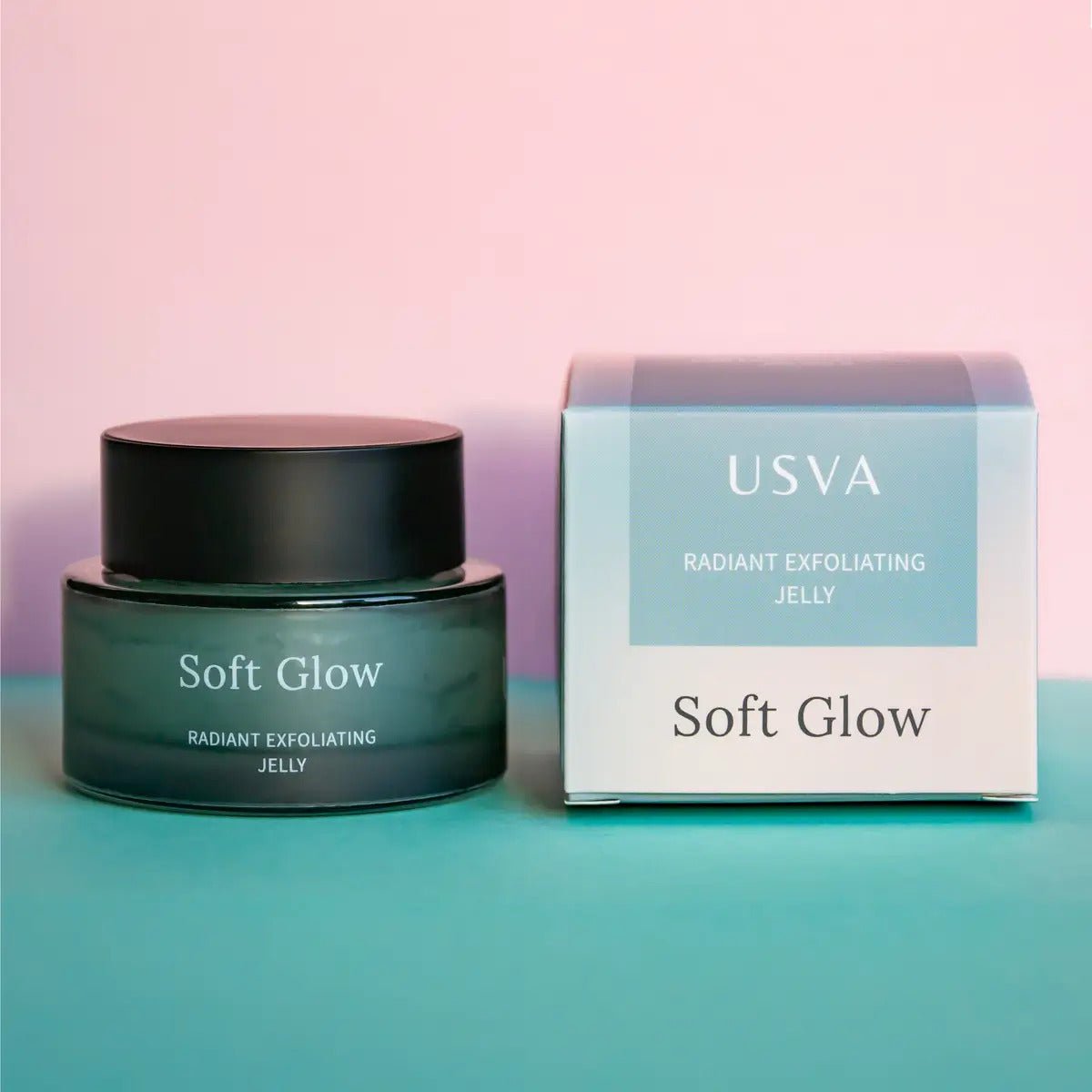 Soft Glow exfolierande jelly i grön glasburk med svart lock bredvid turkos förpackning på rosa-grön bakgrund