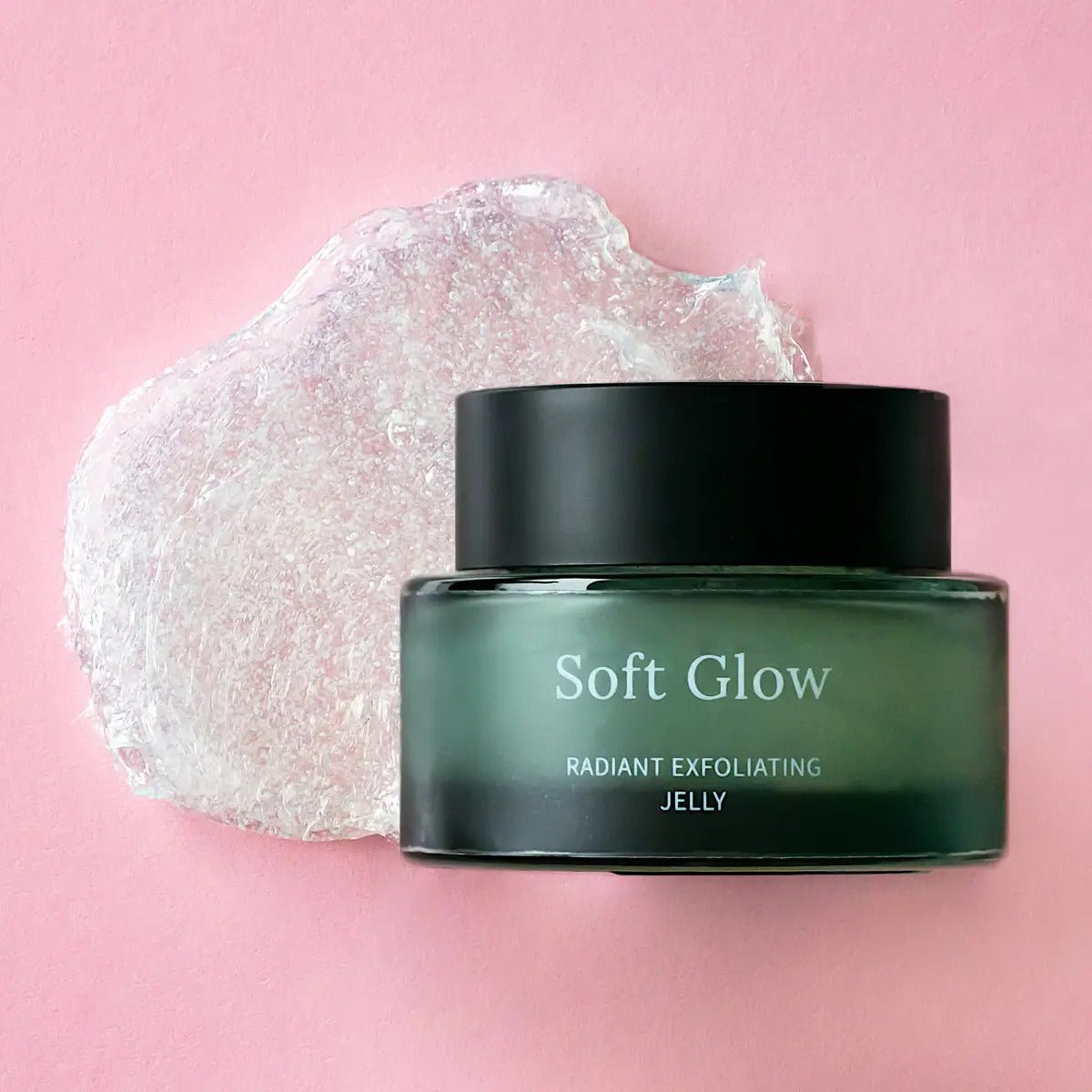 Soft Glow Radiant Exfoliating Jelly i mörkgrön glasburk med svart lock, transparent gelé-textur synlig bakom