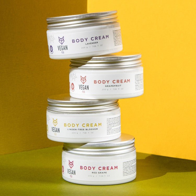 Vit burk med lavendel body cream, silver lock, vegan-märkning, staplade med andra hudvårdsprodukter mot gul bakgrund