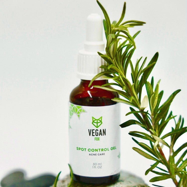 Vegan Fox Spot Control Gel i brun glasflaska med vit etikett och grön text, omgiven av gröna rosmaringrenar