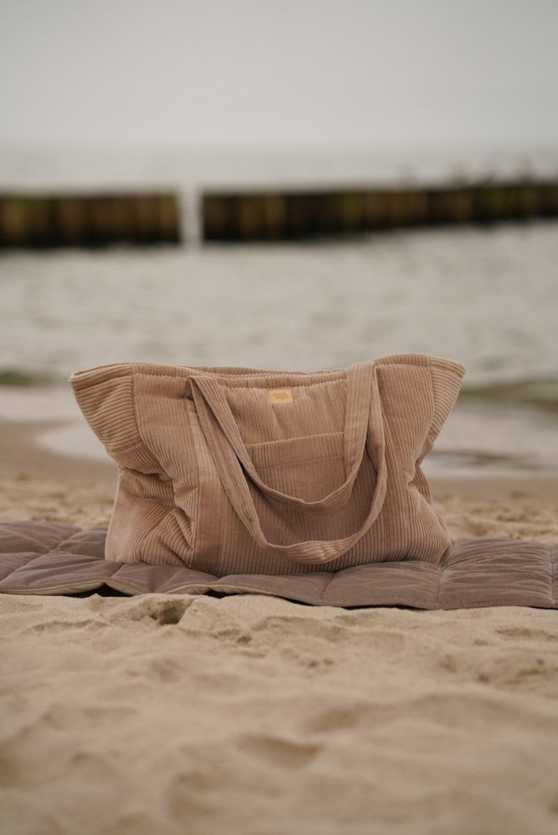 Handgjord weekenderbag i latte sammet från Moi Mili på filt vid stranden