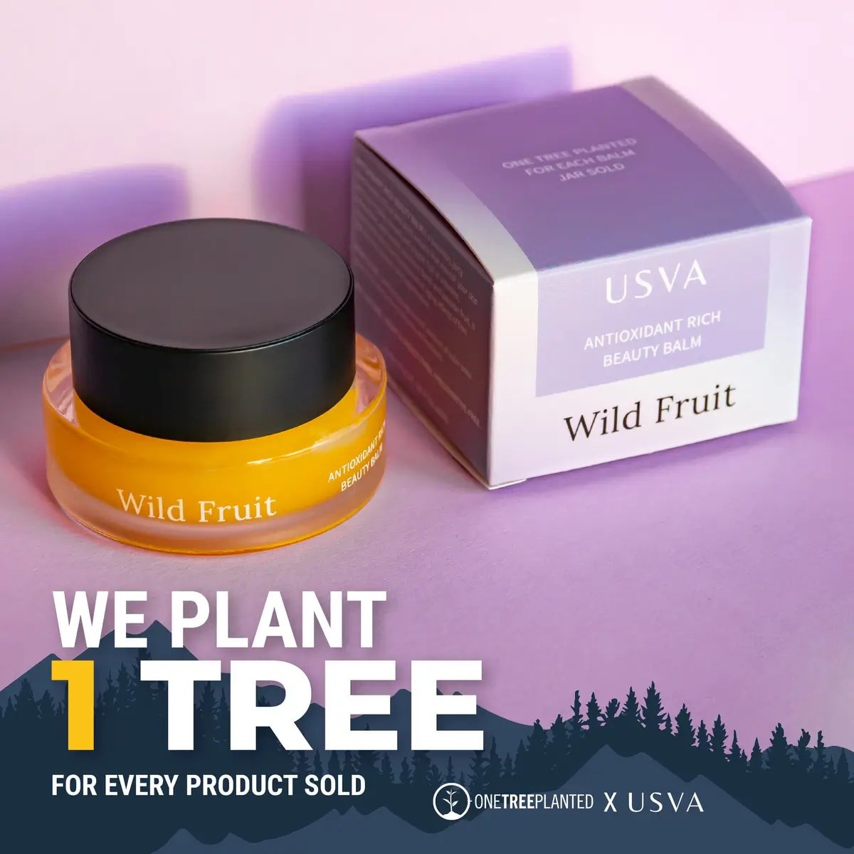 Usva Wild Fruit Beauty Balm i orange glasburk med svart lock bredvid lila förpackning på rosa bakgrund
