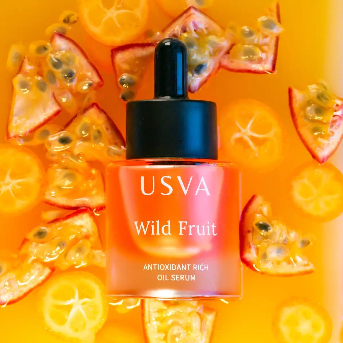 USVA Wild Fruit ansiktsserum i orange glasflaska med pipett, omgiven av färska passionsfruktskivor