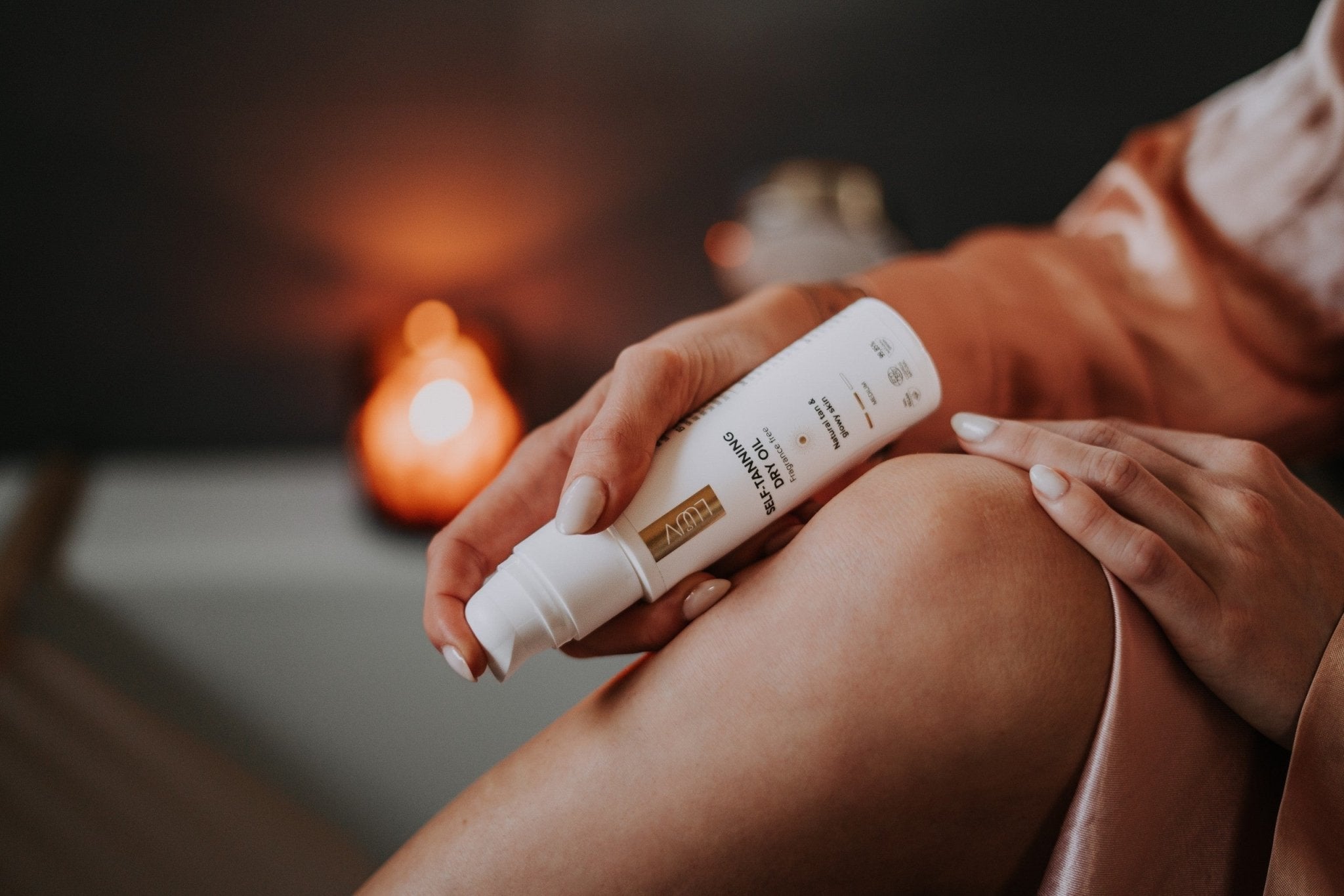 LUUV Brun Utan Sol Torrolja Medium appliceras på benet - vit tube med gulddetaljer hålls i händerna