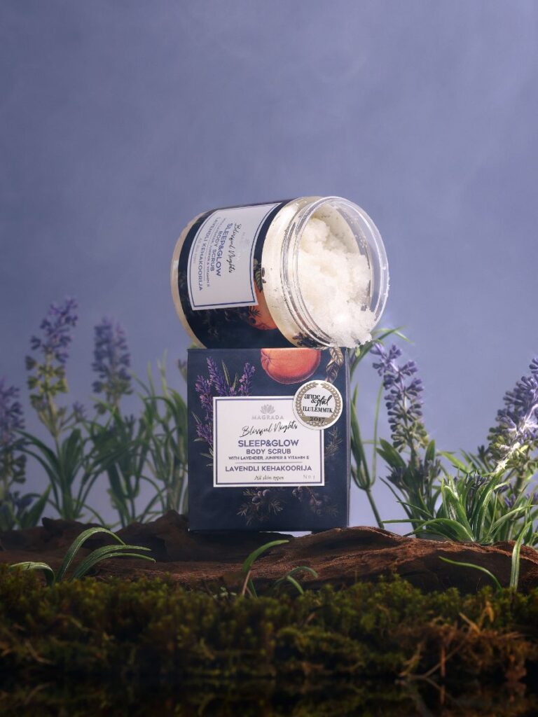 Lavendel kroppspeeling med grapefrukt i mörk glasbehållare med vit etikett, omgiven av lila lavendelblommor