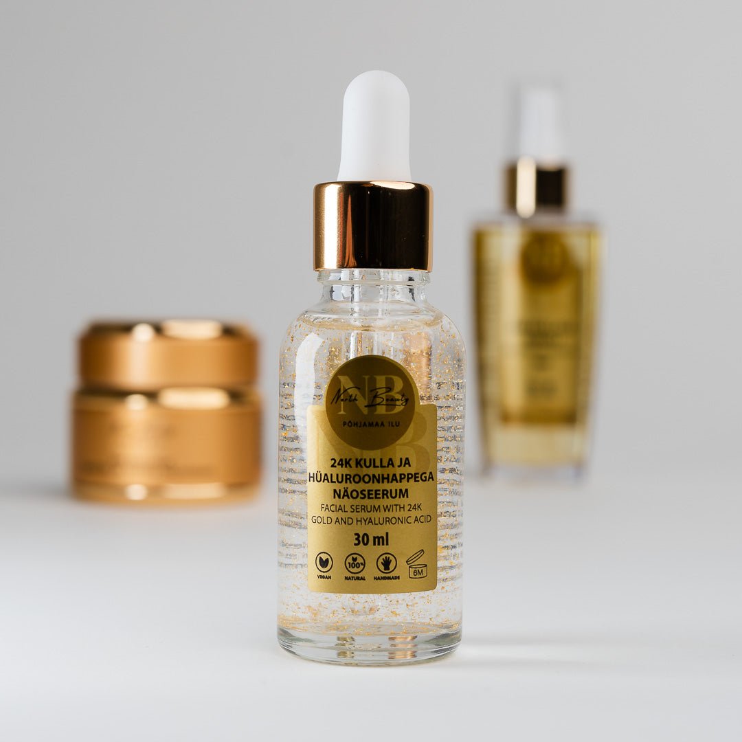 24K Gold Gift Set med gyllene serum i glasflaska med pipett, guldiga hudvårdsprodukter i bakgrunden